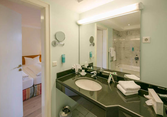 The bathroom has a large mirror and a glossy black washbasin.