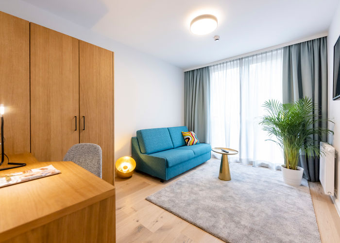 Das modern eingerichtete Zusatzzimmer mit Couch, Teppich, Schrank, Schreibtisch und vielen mehr im Apartment Delux XL.
